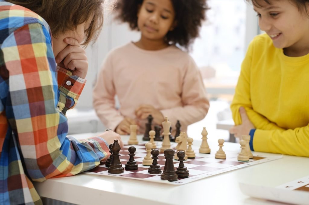 multiethnic-kids-playing-chess-board-game-at-school-e1650351500800.jpg